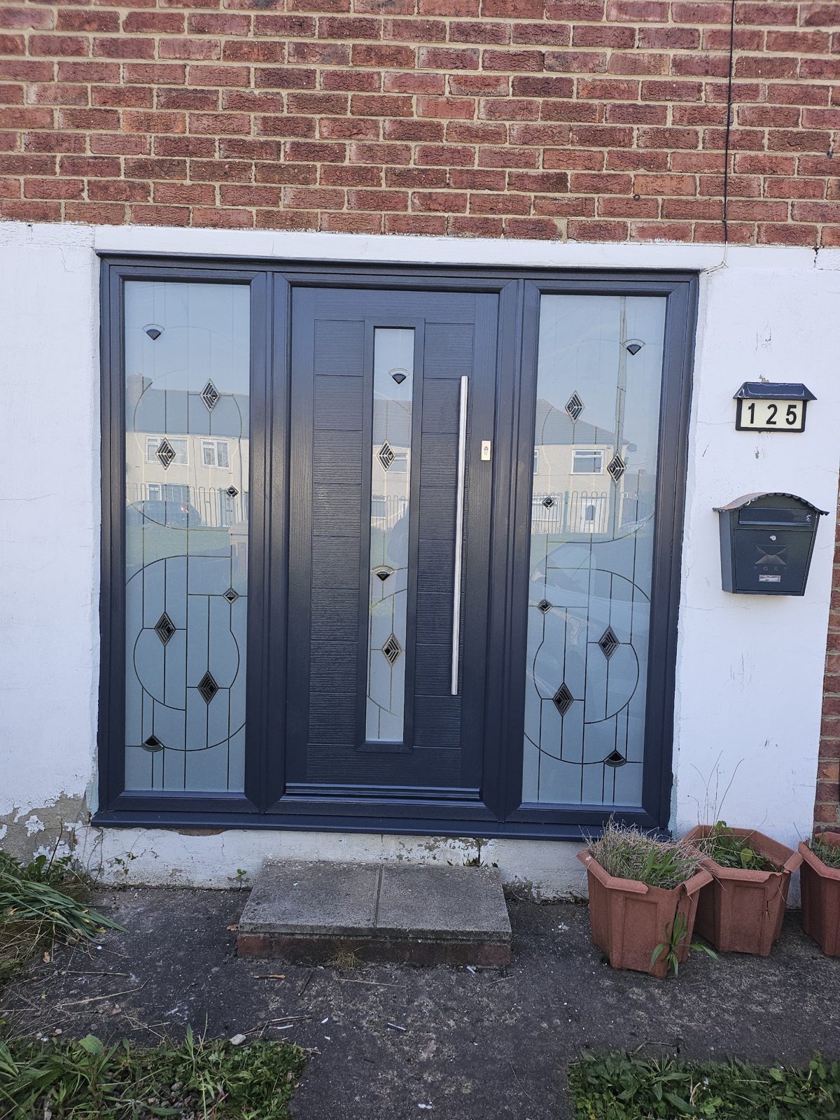After: a new anthracite grey composite front door with matching decorative glass side panels