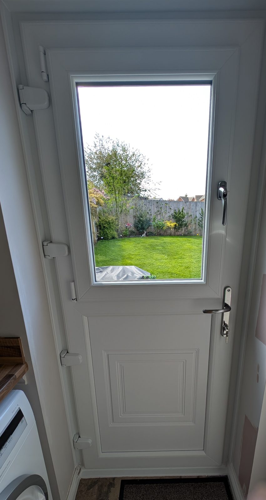 White stable-style back door with a large glass panel looking onto a garden