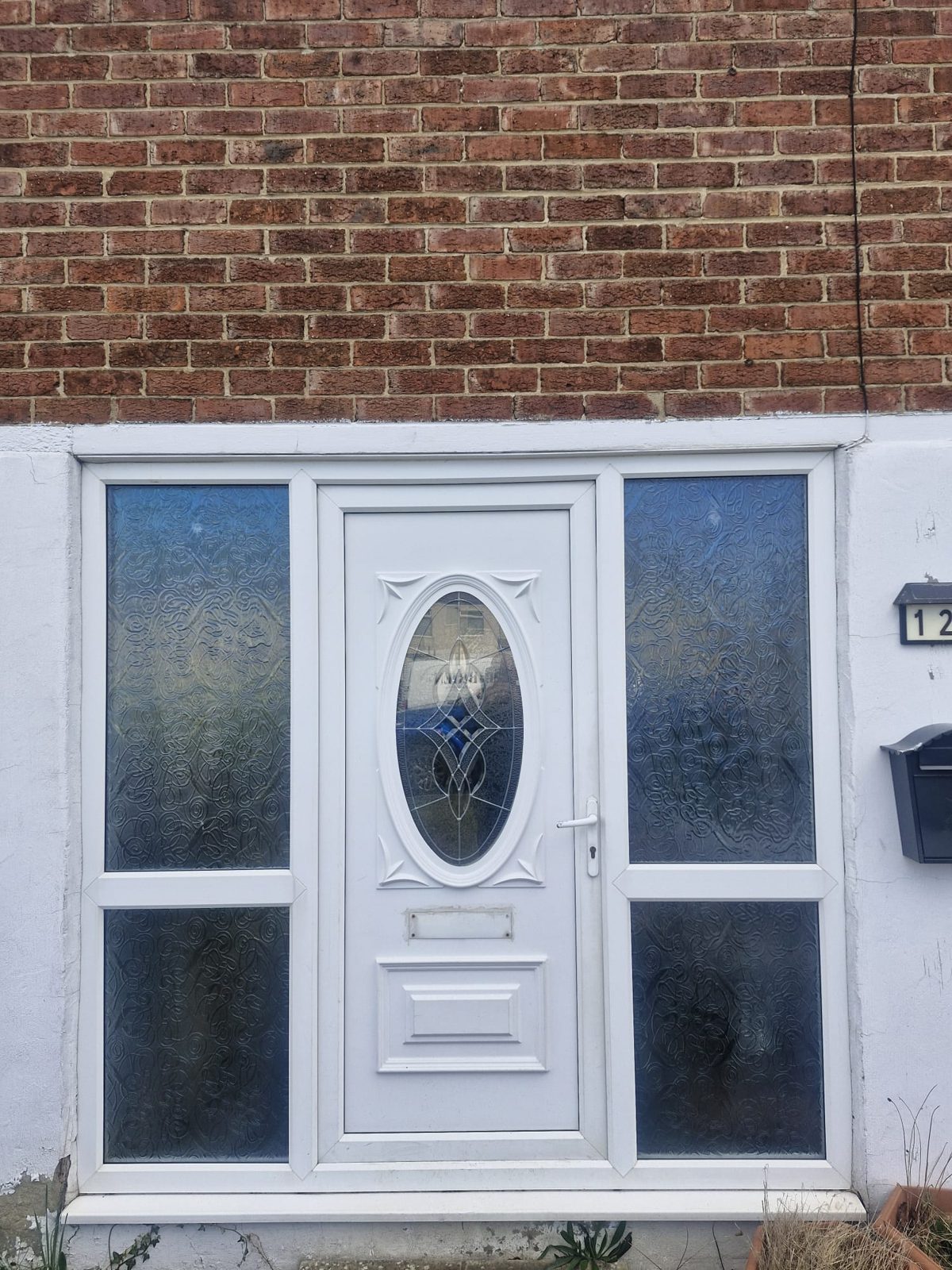 Before: an old white uPVC front door with an oval leaded glass panel and frosted side panels