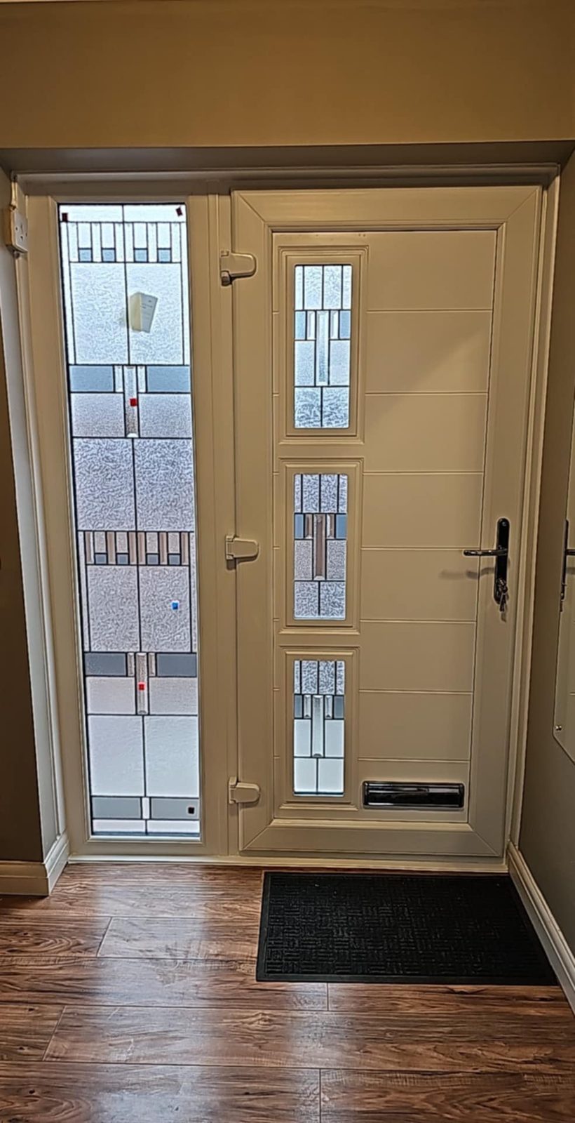 Cream composite front door with a tall leaded art-glass side panel, seen from inside