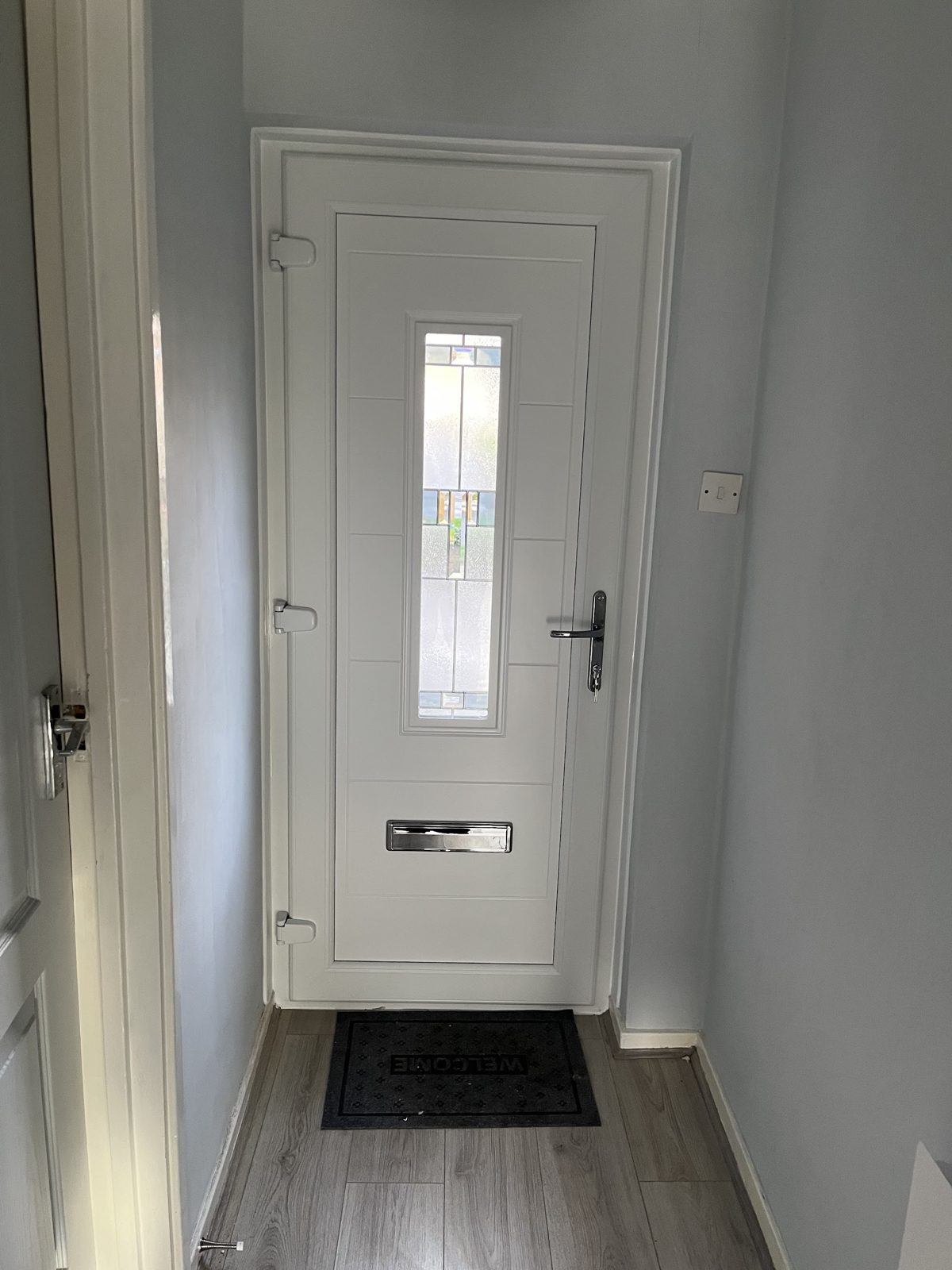 White composite front door with a decorative glass strip, fitted in a hallway